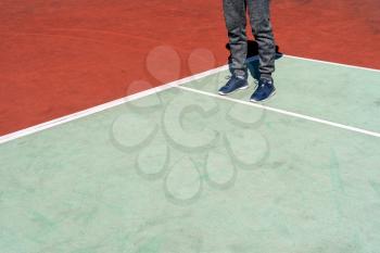 Man wearing sneakers and grey sports pants on a tennis court