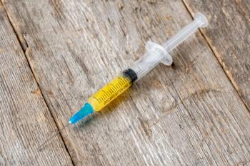 Syringe with yellow liquid lying on wooden background