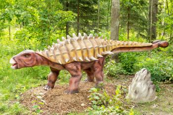 Statue of Ankylosaurus dinosaur in a green forest