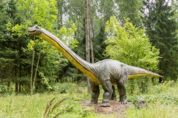 Statue of realistic Diplodocus dinosaur in a wild forest