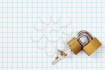 Two linked padlocks lying on squared paper background
