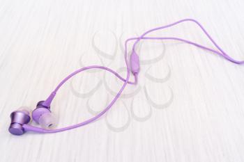 Purple earphones on wooden background.The concept of music, sports, active lifestyle.