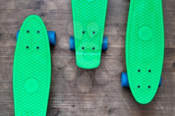 Three green skateboards on wooden background, top view