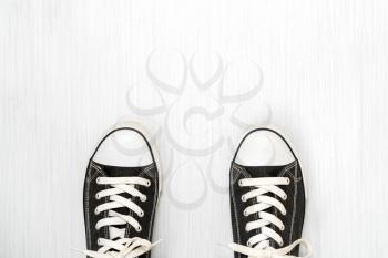 Black sneakers on a wooden background, empty space at the top