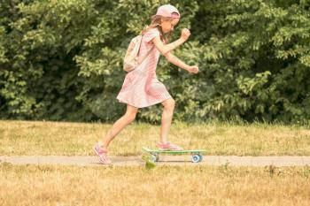 Child girl skateboarding in a summer sunny park