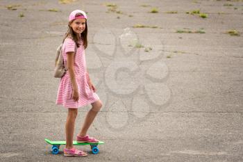 Urban girl ride with penny skateboard on asphalt street
