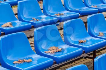 Empty plastic seats at small city stadium during autumn season