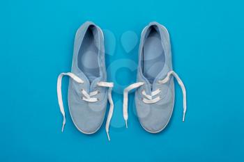 Flat lay of soft blue color canvas shoes on blue background 