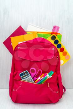 Back to school concept. Backpack with school supplies on the wooden background.