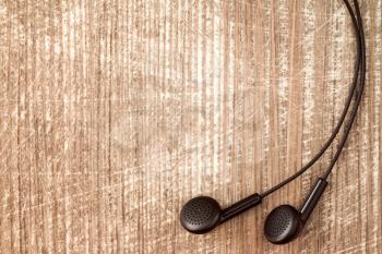 Black earphones on wooden background with copy-space