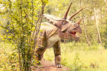 Statue of Triceratops dinosaur in a green forest
