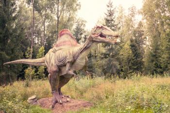 Statue of Spinosaurus dinosaur in a green forest