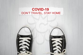 Shoes and note with phrase Don't travel, stay home.Stop coronavirus. Self isolation. Home quarantine from Covid-19. Recommendation to prevent spreading Coronavirus, Covid 19 lockdown.