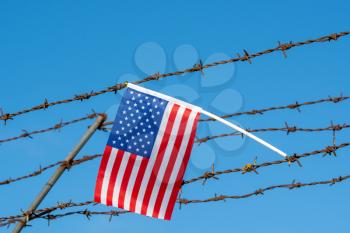 American flag on barbed wire fence. Borders protection,social issues on refugees or illegal immigrants