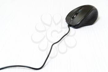 Black computer mouse with cord on white wooden background