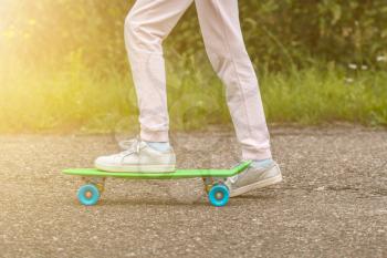 Close-up of skateboarder legs. Girl ride skateboard on a sunny day