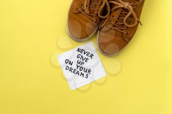 Brown sneakers and handwriting on a napkin - Never Give Up On Your Dreams 