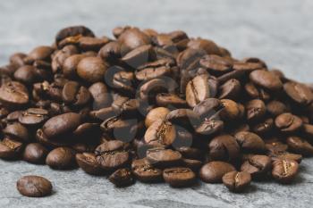 Roasted coffee beans pile on grey stone background