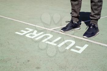 Man legs in sneakers standing next to line and word FUTURE