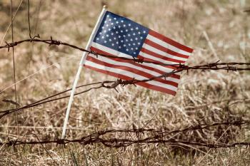 American flag on old barbed wire fence in a grass