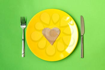 Plate with paper heart and cutlery on green background, flat lay. Healthy diet concept