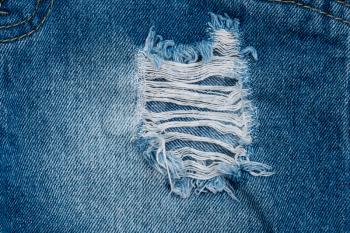 Hole and Threads on Denim Jeans. Close up blue jean texture 