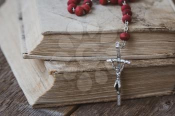 Catholic rosary with a cross lie on several ancient books