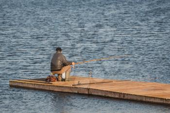 Unrecognizable rear view of  senior man fishing on the lake