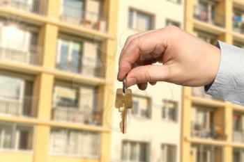 Real estate agent holds key on blurred building background