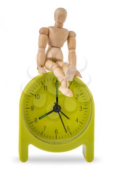 Wooden mannequin sits on green alarm clock isolated on white background