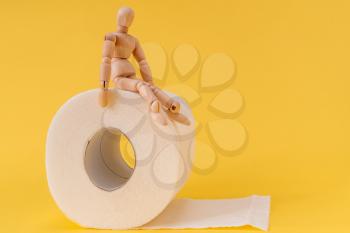 Wooden mannequin sit on a roll of toilet paper. Concept for constipation and bowel movement