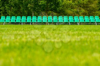 Empty sports field with a plastic seats for spectators. Selective focus on a row of plastic chairs.