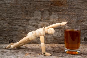 Alcohol addiction - wooden man reaching a glass of whiskey