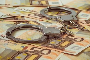Handcuffs on the background of 50 euro.Financial crime, dirty money and corruption concept.