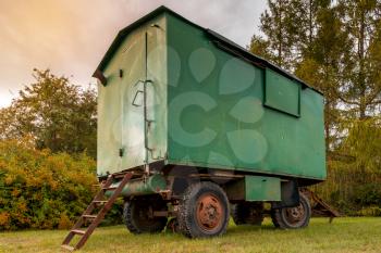 Old green rusty construction camper, trailer, van or wagon. Temporary housing for construction workers.