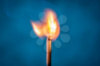 Ignition of a match, with smoke on blue background. A beauty of burning match. Fire styling.