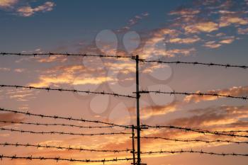 Silhouette of barbed wire fence with twilight sky to feel silent and lonely and want freedom.