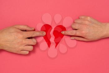Love and relationship problems concept - male and female hands holding two parts of broken heart