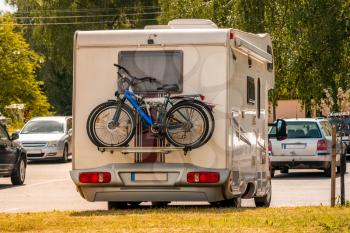 Two pleasure bikes are strapped to the back of the camper van. Rear view. Leisure trip in the summer.