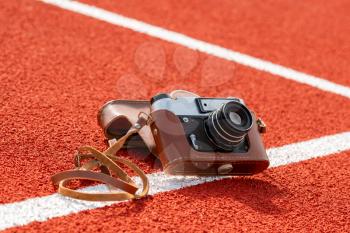 Retro camera on the running track in stadium, sport journalism concept