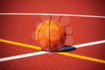 Basketball on the center of outdoor court. Orange ball and court lines on a street court.