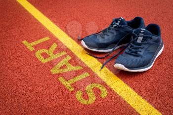 Running shoes are placed beside the start line on race track