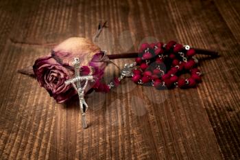 Catholic rosary and wilted rose, close-up view. Faith and hope concept.