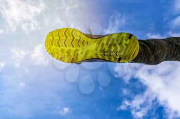 Running and jumping over the camera. Running shoe on sky background,  low angle view