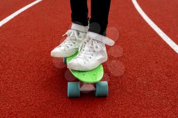 Skater girl rides on penny board in the school stadium