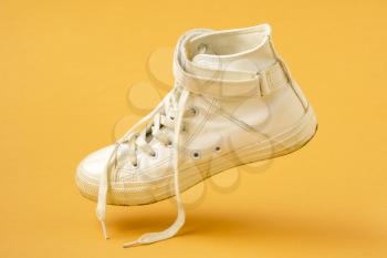 White leather shoe falling on the yellow background