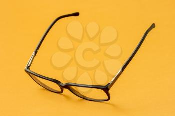 Eyeglasses with black frame on yellow background. Ophthalmology theme.