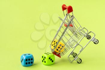 Buying games. Shopping cart with colorful dice on green background. 