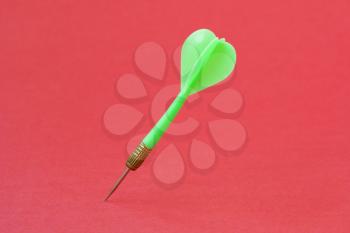 Green dart arrow on the red background. Copy space.