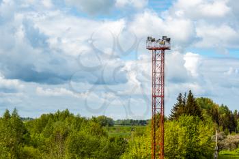 Tall tower with spot lights or lamps for railroad against  sky background with white clouds 